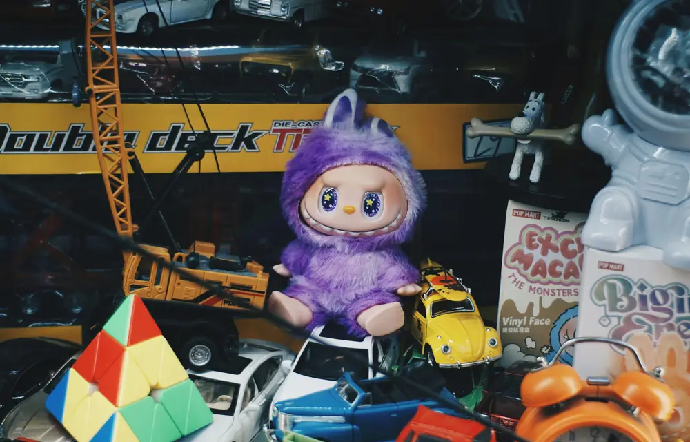 A scattered arrangement of art toys, mixing early internet-era toys with later-generation designer collectibles, with a purple Labubu placed at the center.